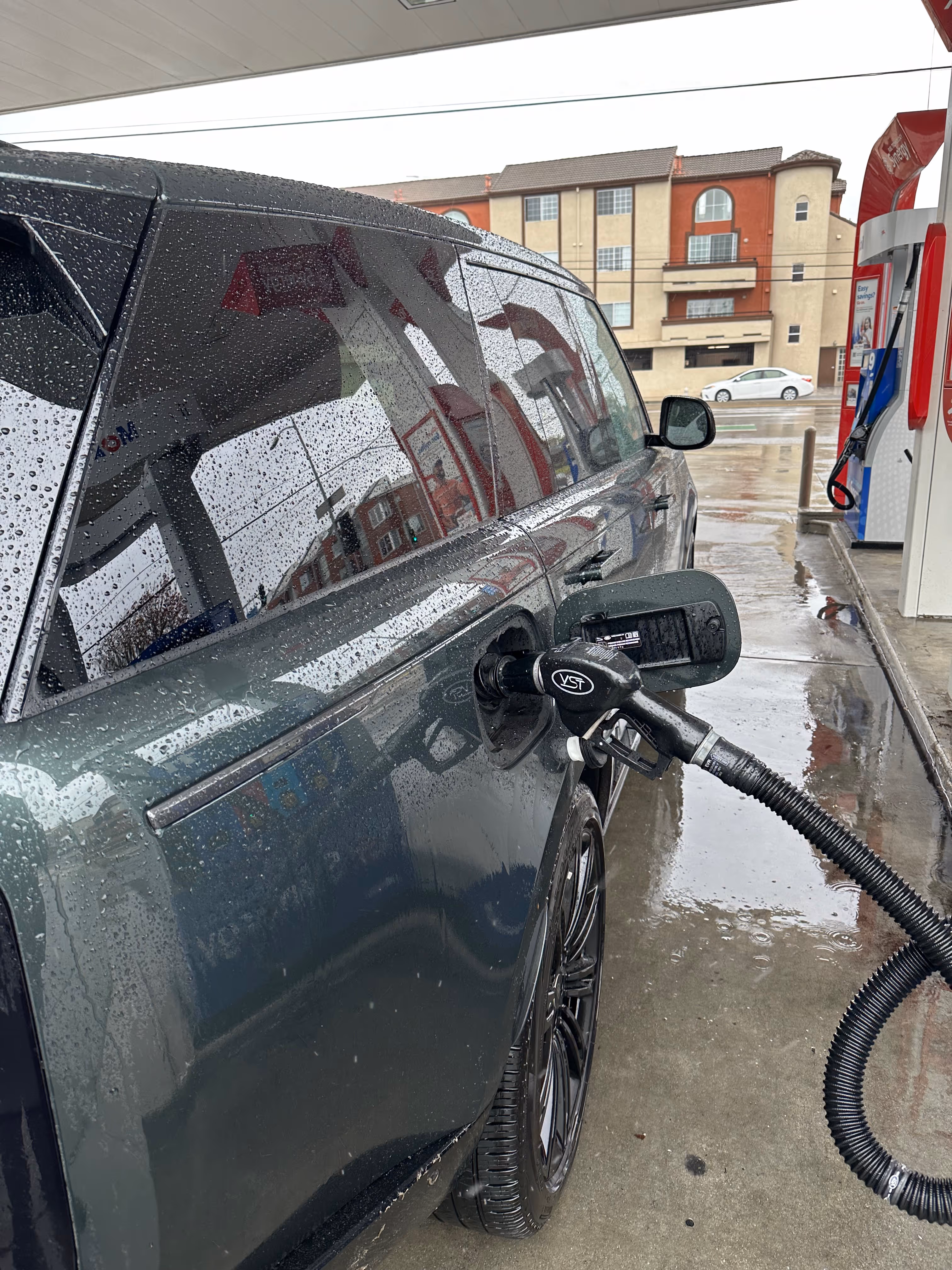 Car refueling at a gas station with fuel pump nozzle inserted