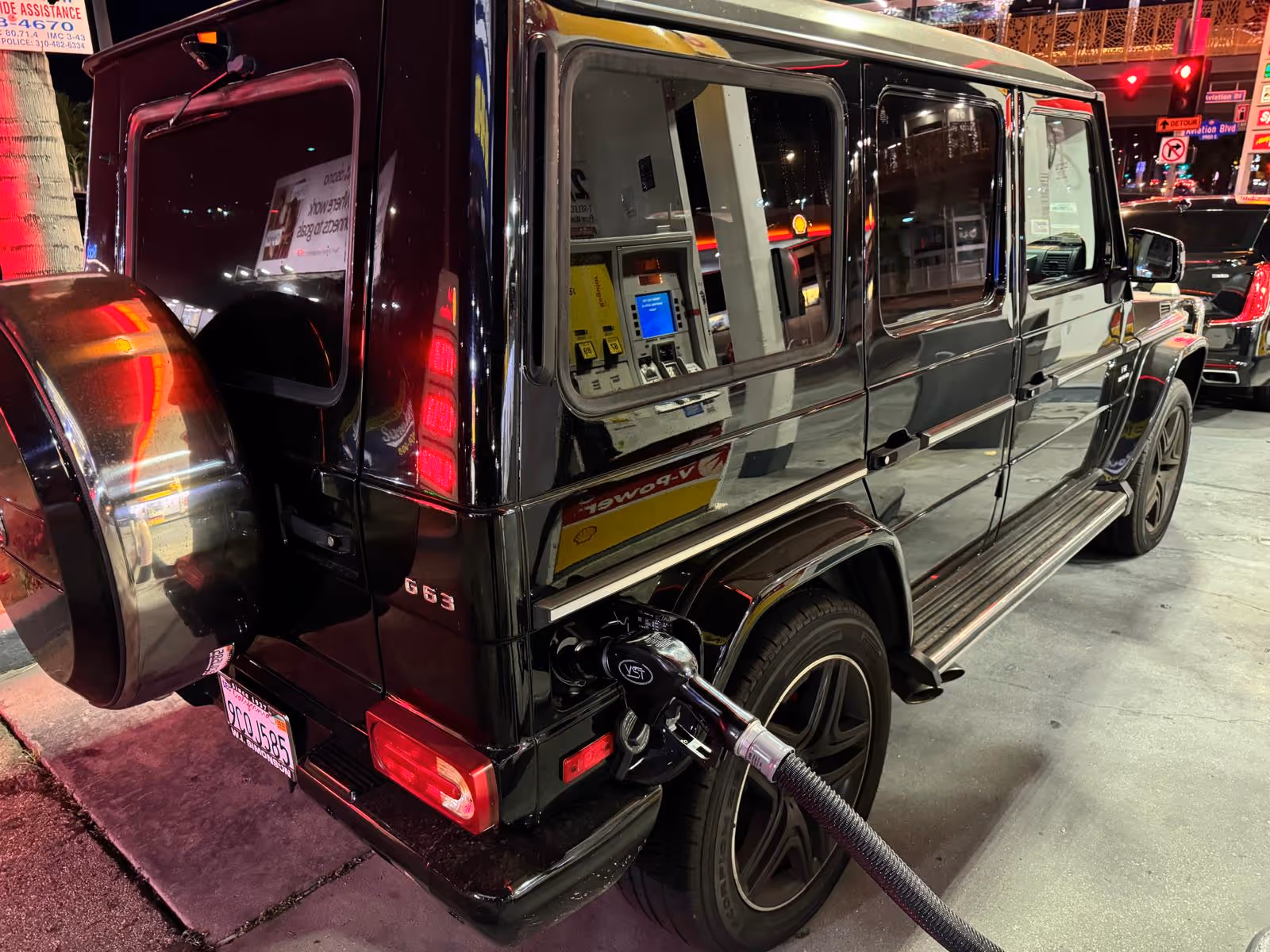 Car refueling at a gas station with fuel pump nozzle inserted