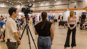 Two staff members interviewing Ambassador Anja Christoffersen at Brisbane 2024