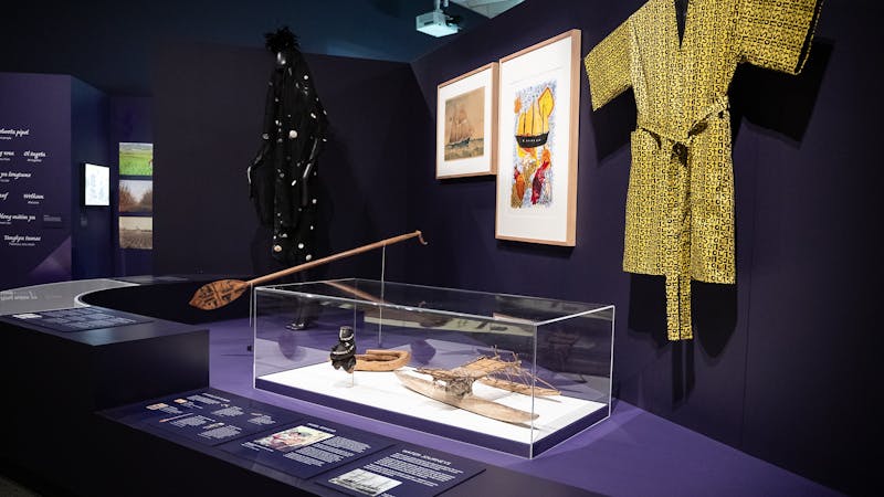 An exhibition space with objects on display including a yellow smoking jacket