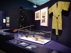 An exhibition space with objects on display including a yellow smoking jacket