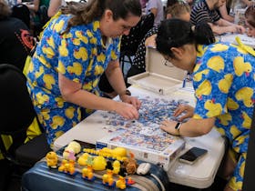 Two women in duck outfits complete a puzzle