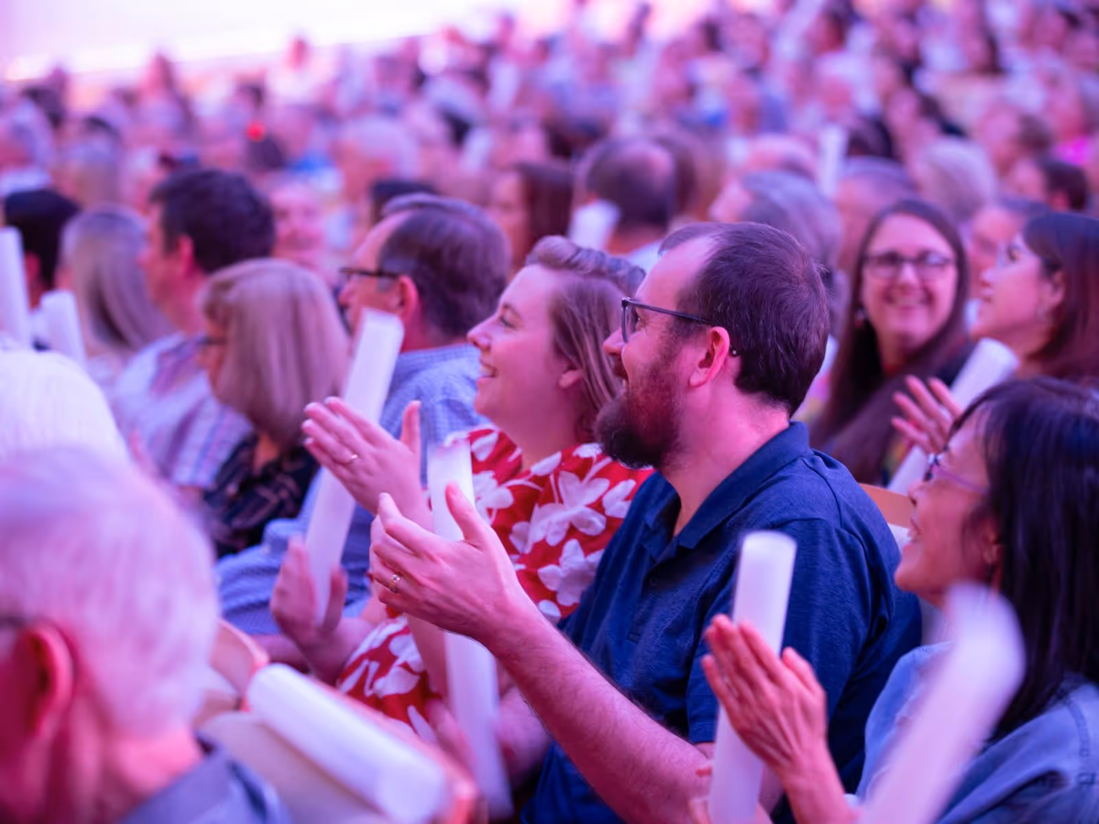 In a crowd shot, the image focuses on two people smiling and clapping their hands.
