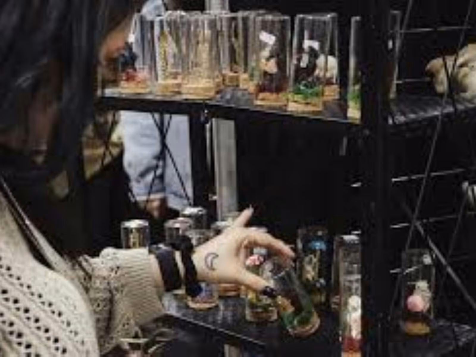 Phto of a lady with black hair looking at jars full of coloured items