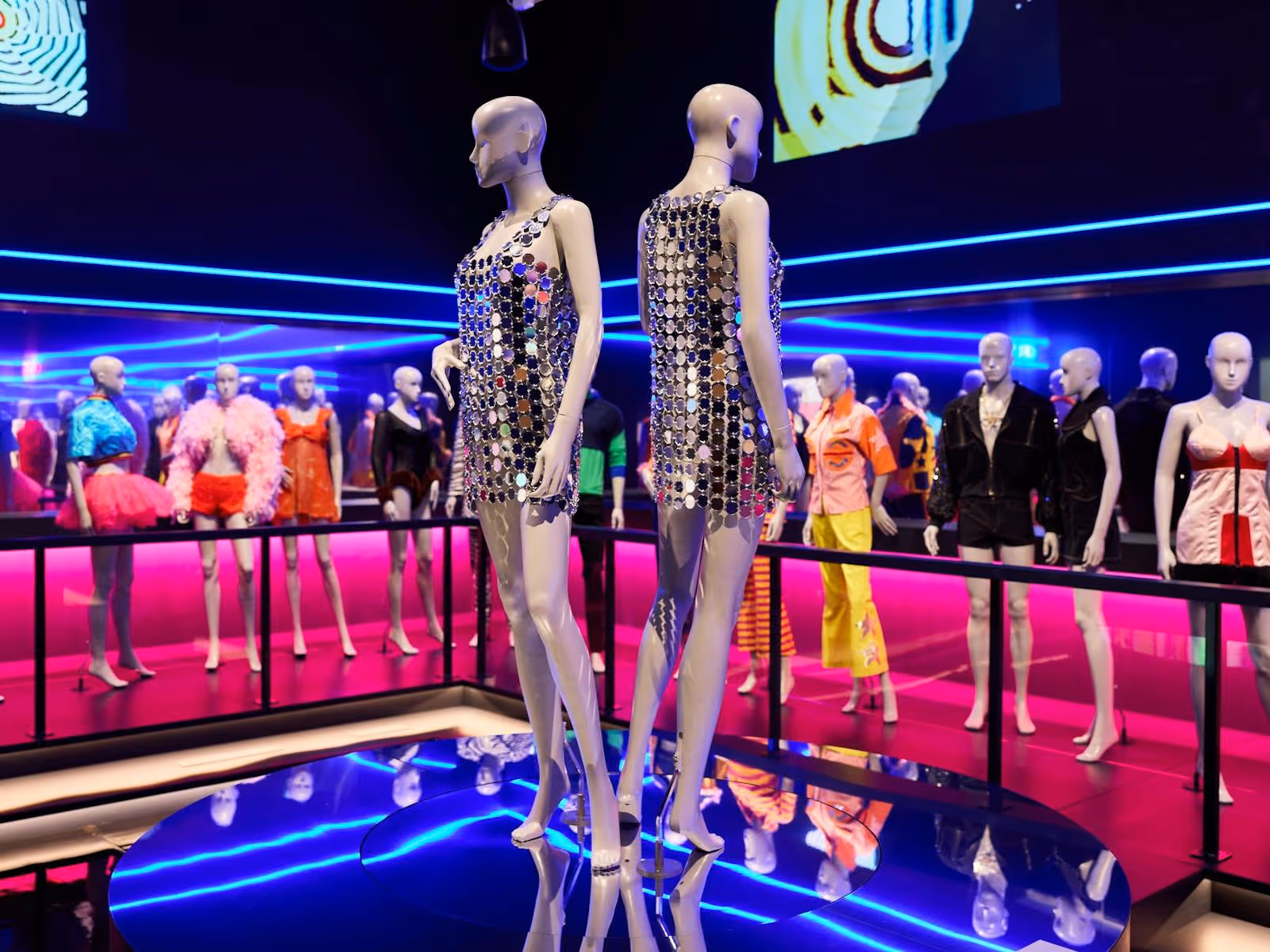 Two mannequins dressed in reflective mirror ball sequin dresses in a night club scene.
