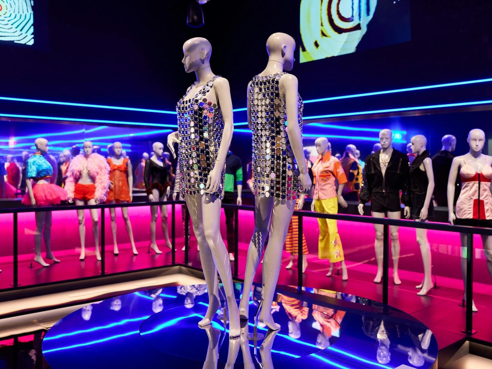 Two mannequins dressed in reflective mirror ball sequin dresses in a night club scene.