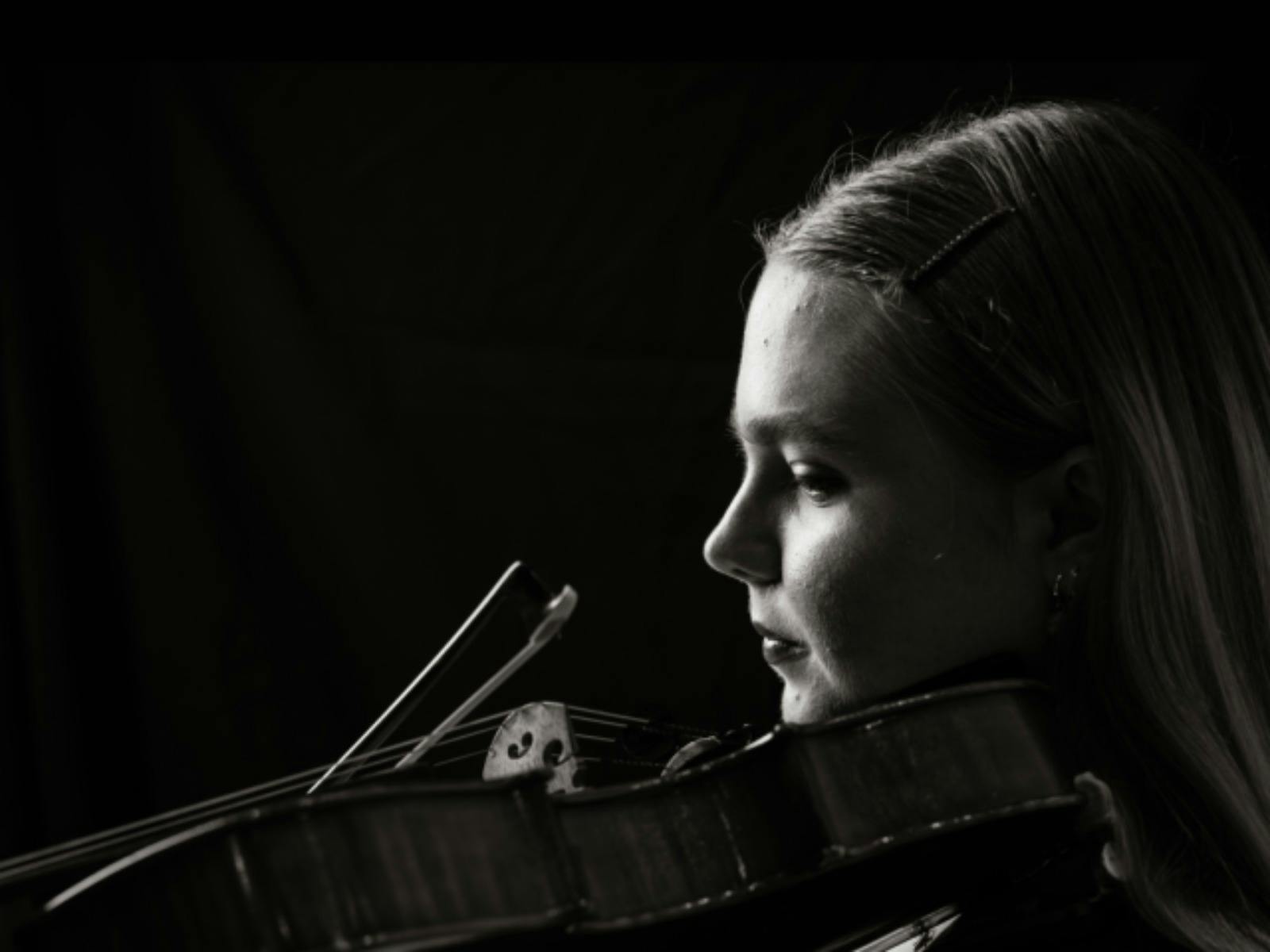 Black-and-white portrait of a violist in profile, looking toward the light