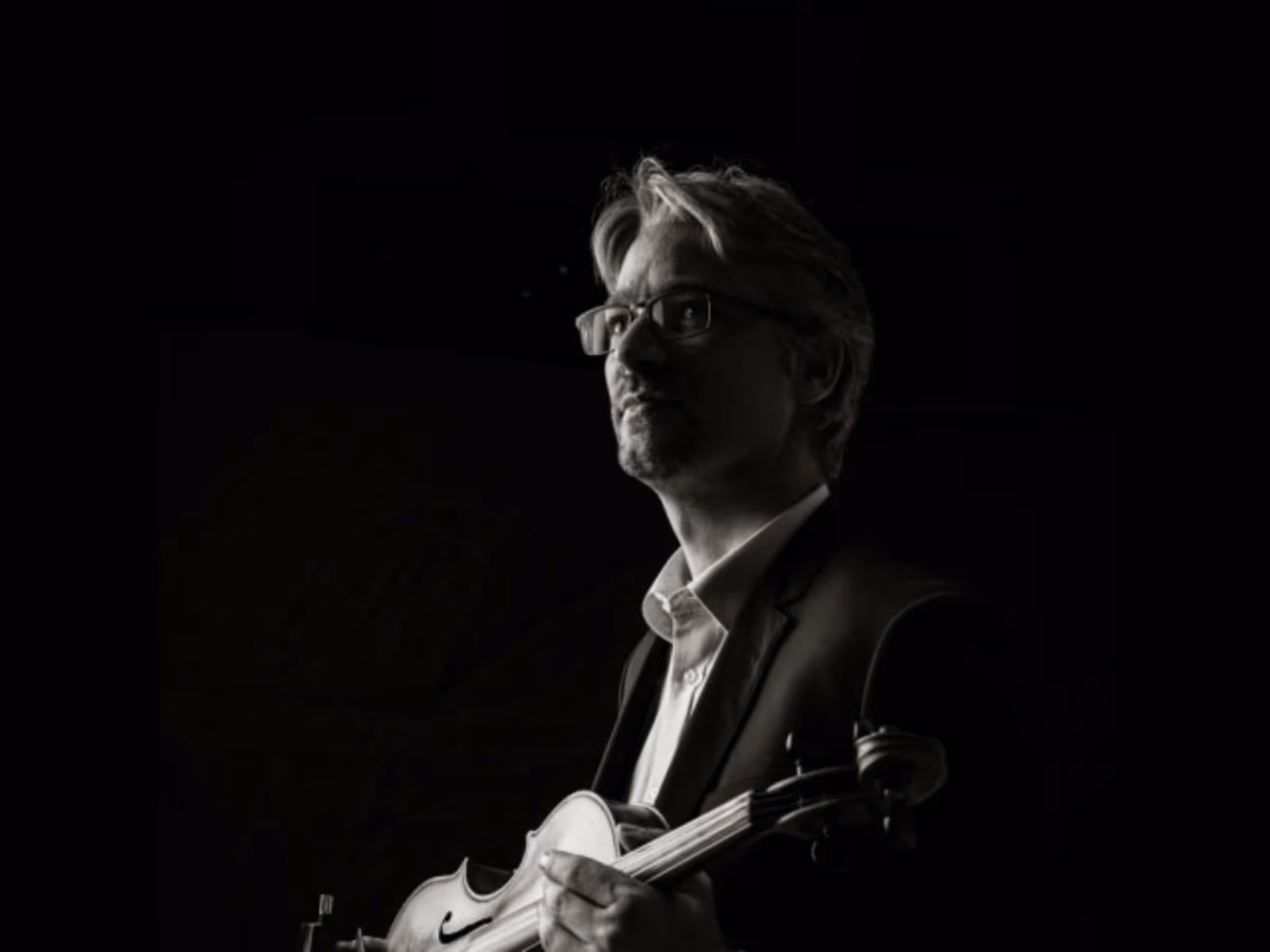 Black-and-white portrait of a violist in profile, looking toward the light