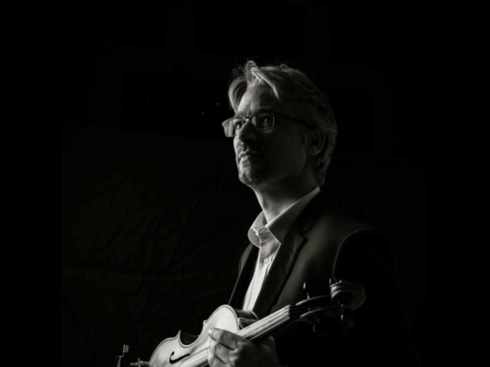 Black-and-white portrait of a violist in profile, looking toward the light