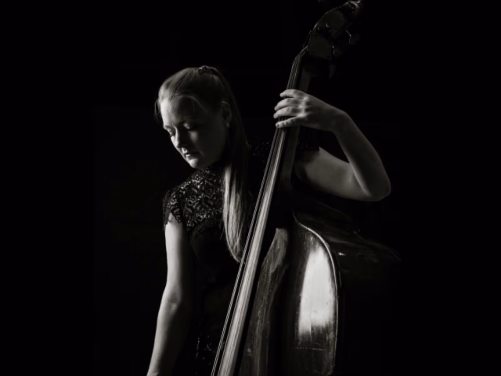 Black-and-white portrait of a double bassist in profile, looking toward the light
