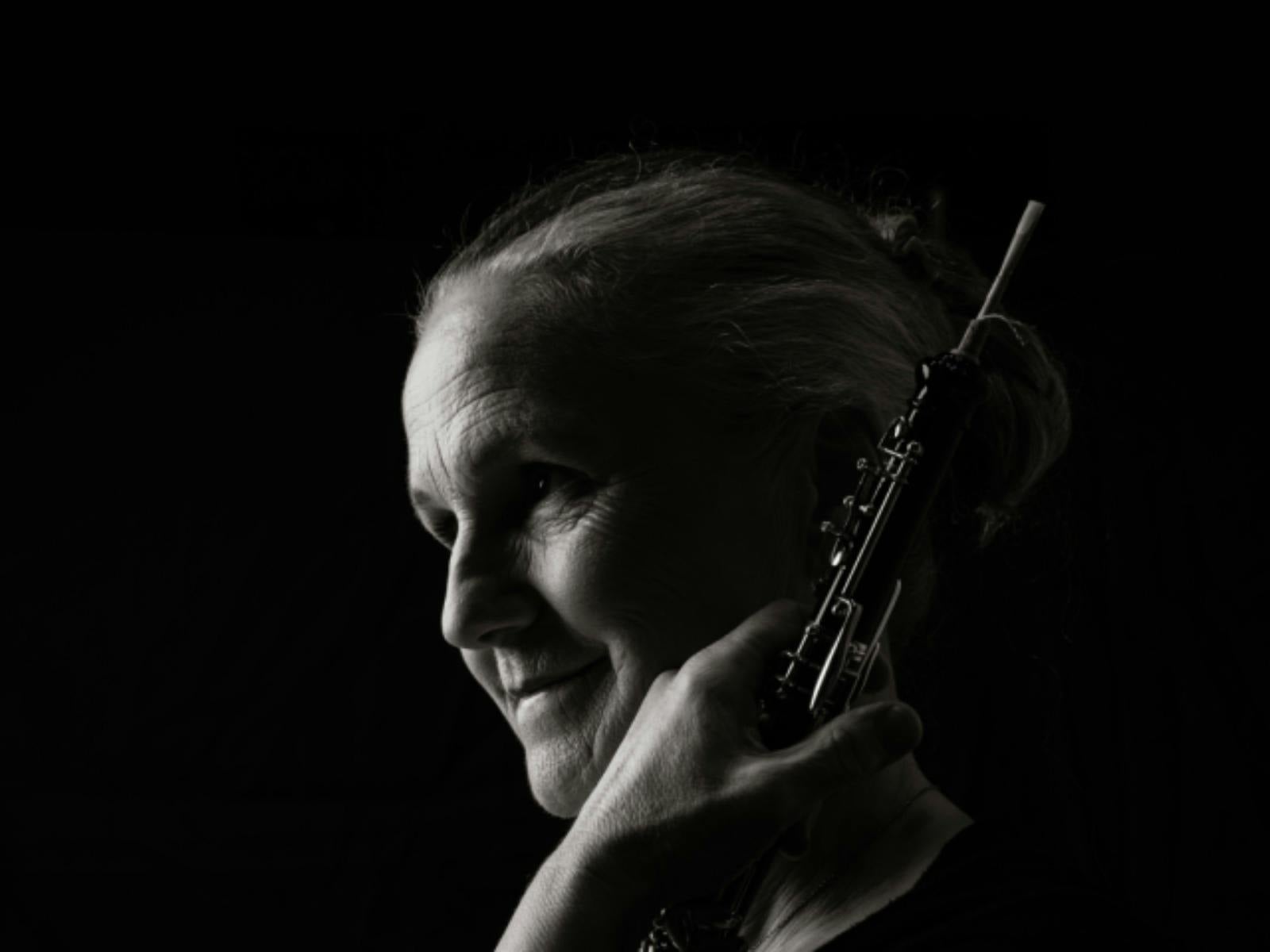 Black-and-white portrait of an oboe player in profile, looking toward the light