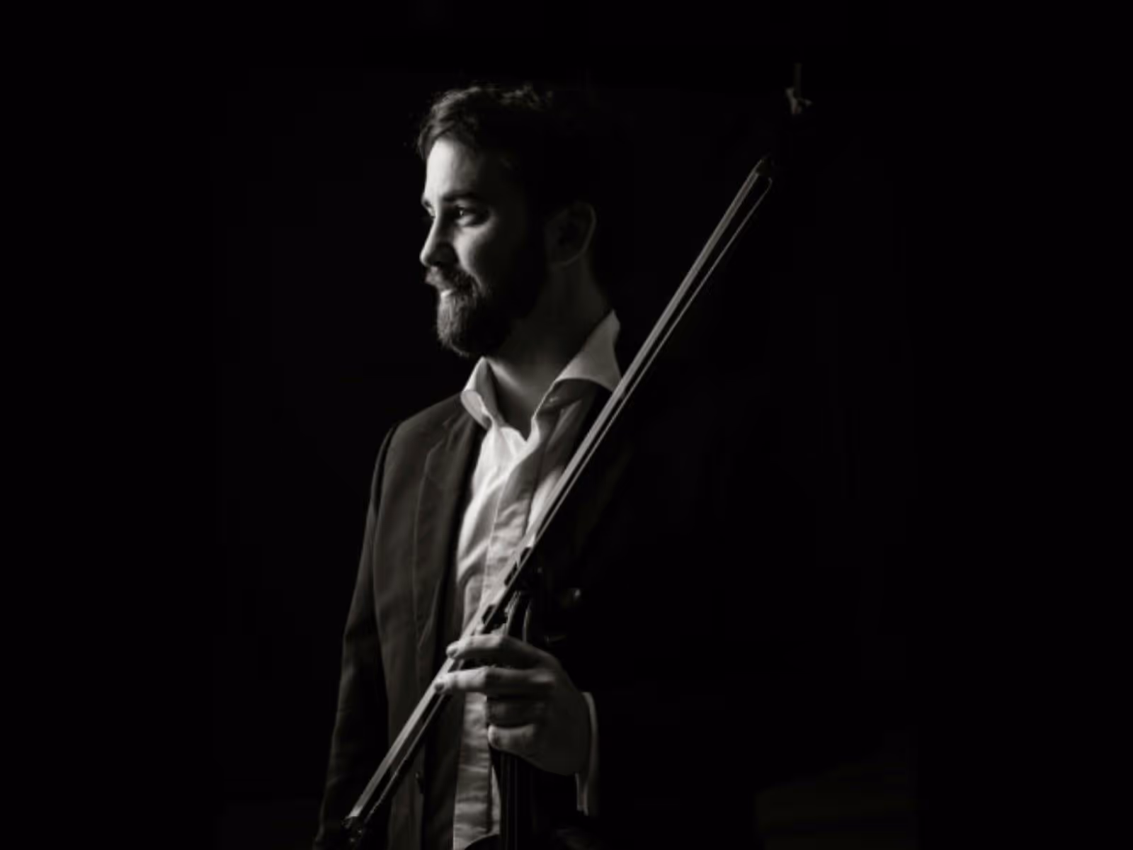 Black-and-white portrait of a violinist in profile, looking toward the light