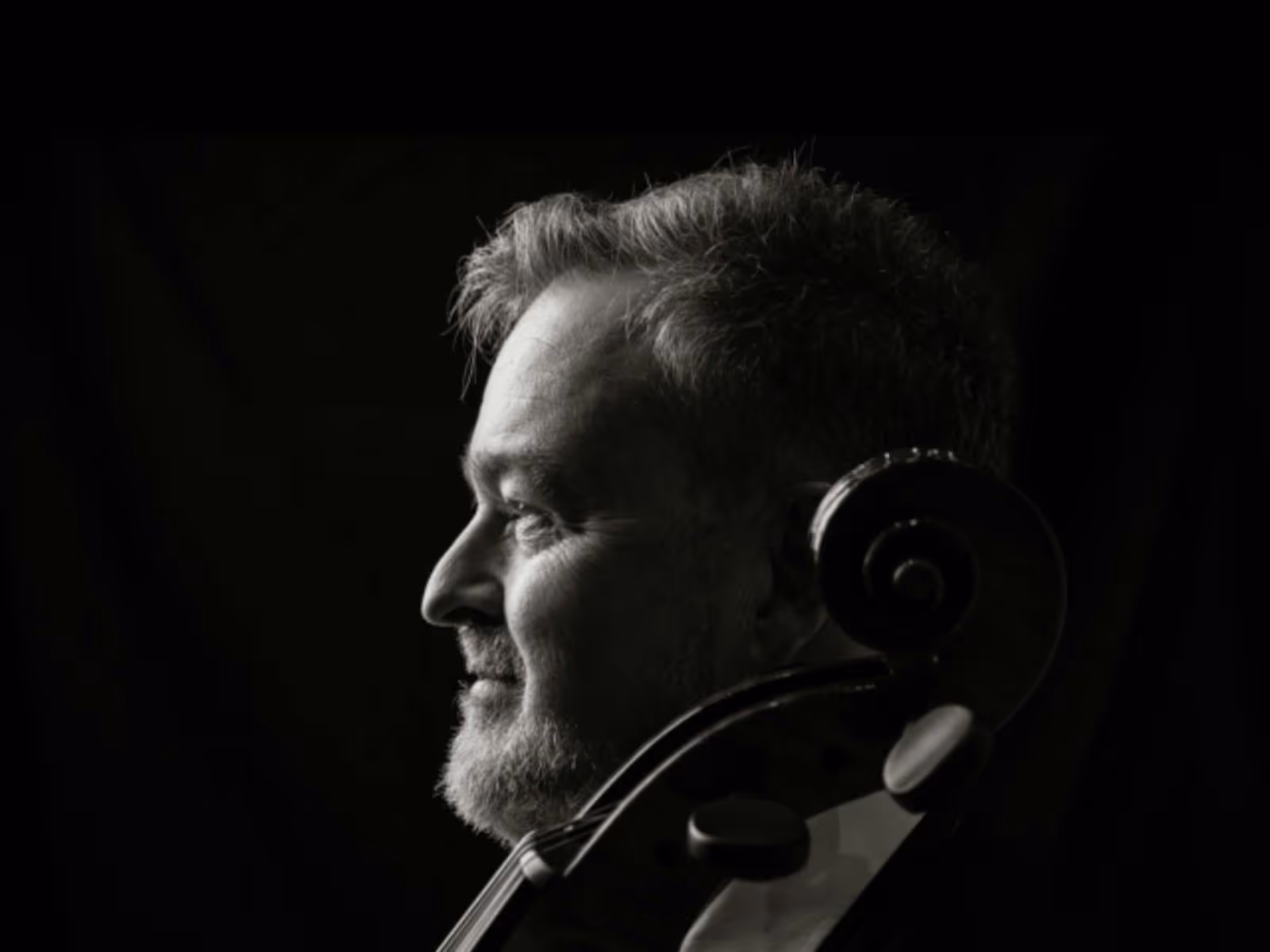 Black-and-white portrait of a cellist in profile, looking toward the light
