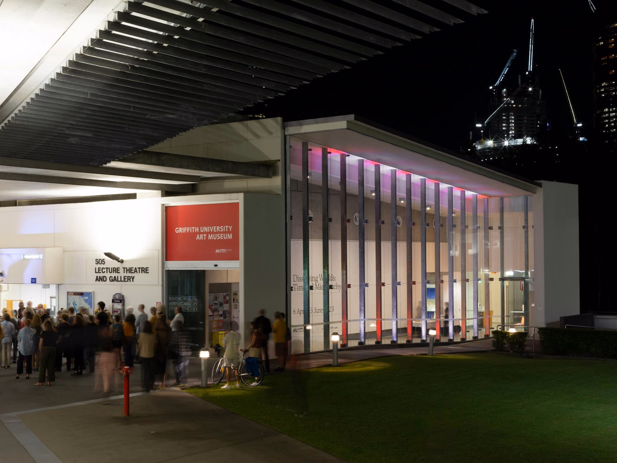 Griffith University Art Museum from the exterior at night. A large crowd is infront of the gallery.
