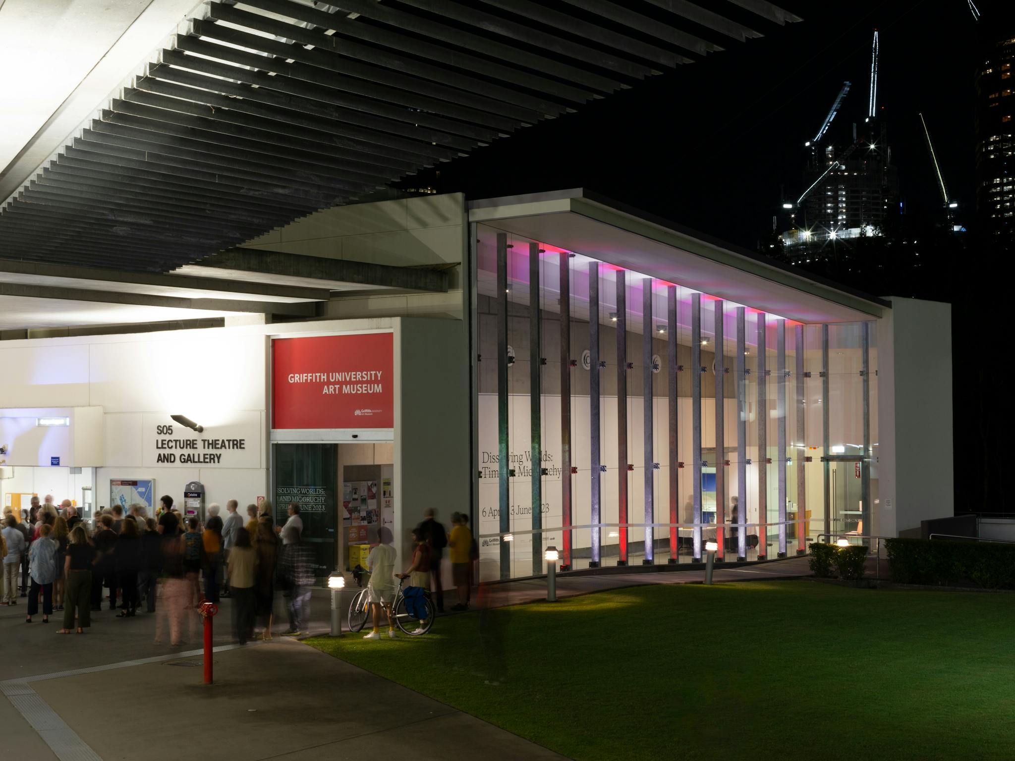 Griffith University Art Museum from the exterior at night. A large crowd is infront of the gallery.