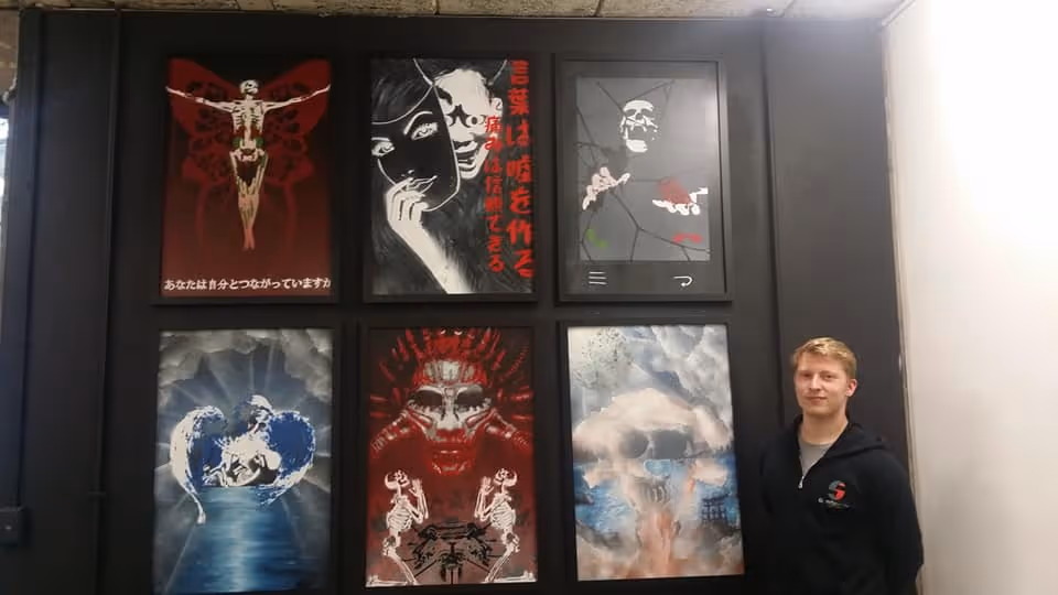 Daniel Price standing in front of his artwork portfolio