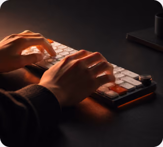 Hands typing on a backlit keyboard