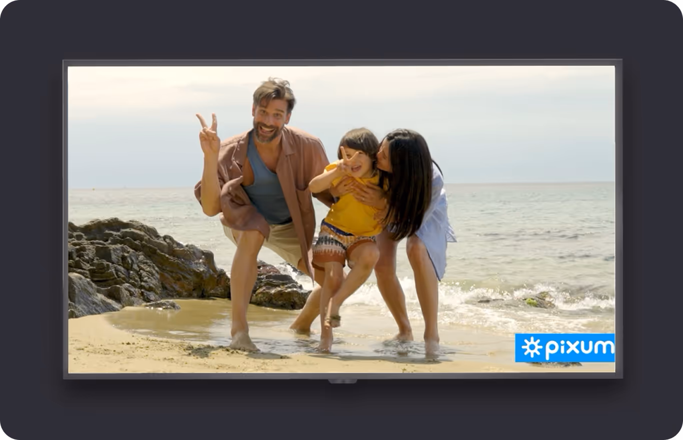 A happy family poses for a photo on a beach, displayed on a television screen with a pixum logo in the corner.