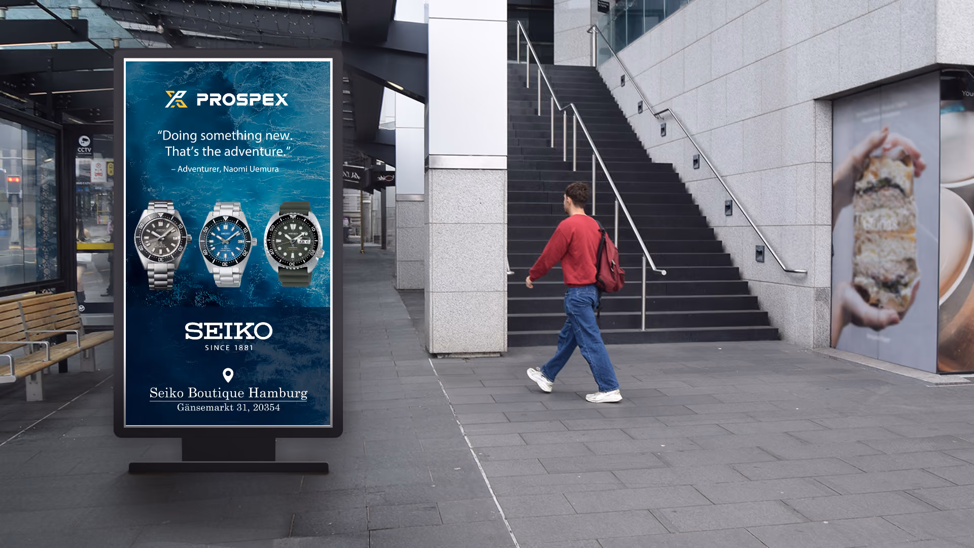 Street display (DOOH) advertises three Seiko Prospex watches in front of a man walking on a staircase in the city.