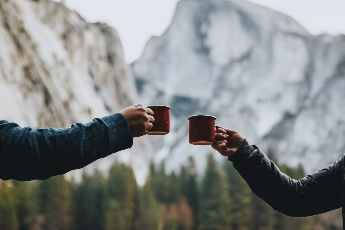 An image of two people holding up mugs to make a cheers