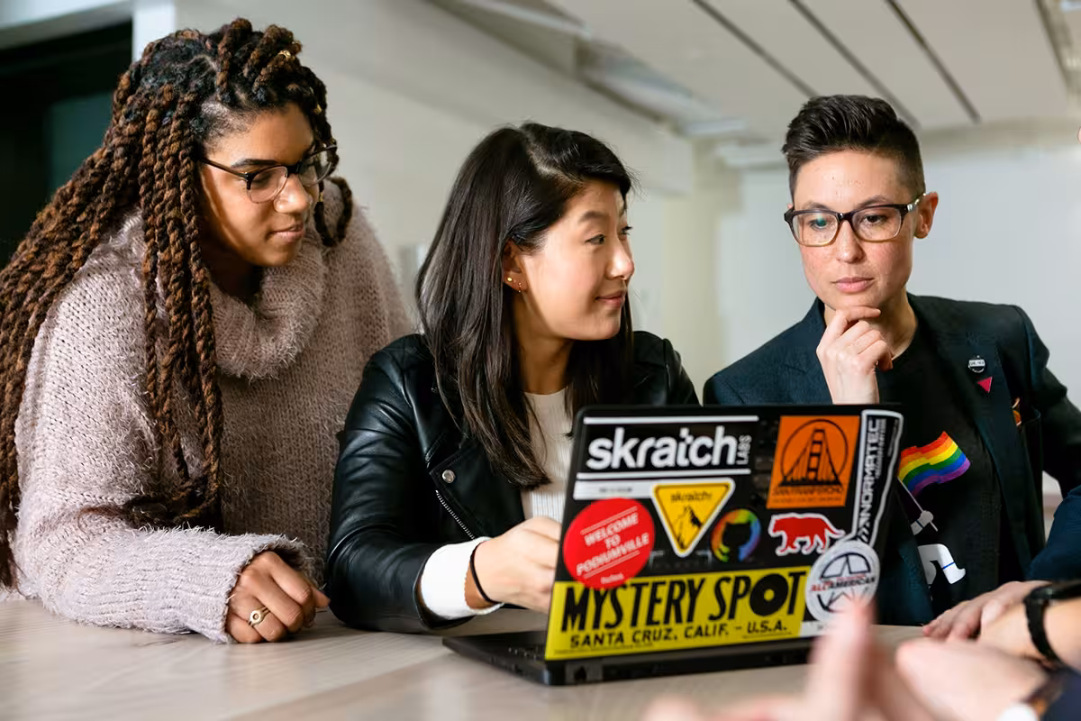 An image depicting three people looking at a laptop screen