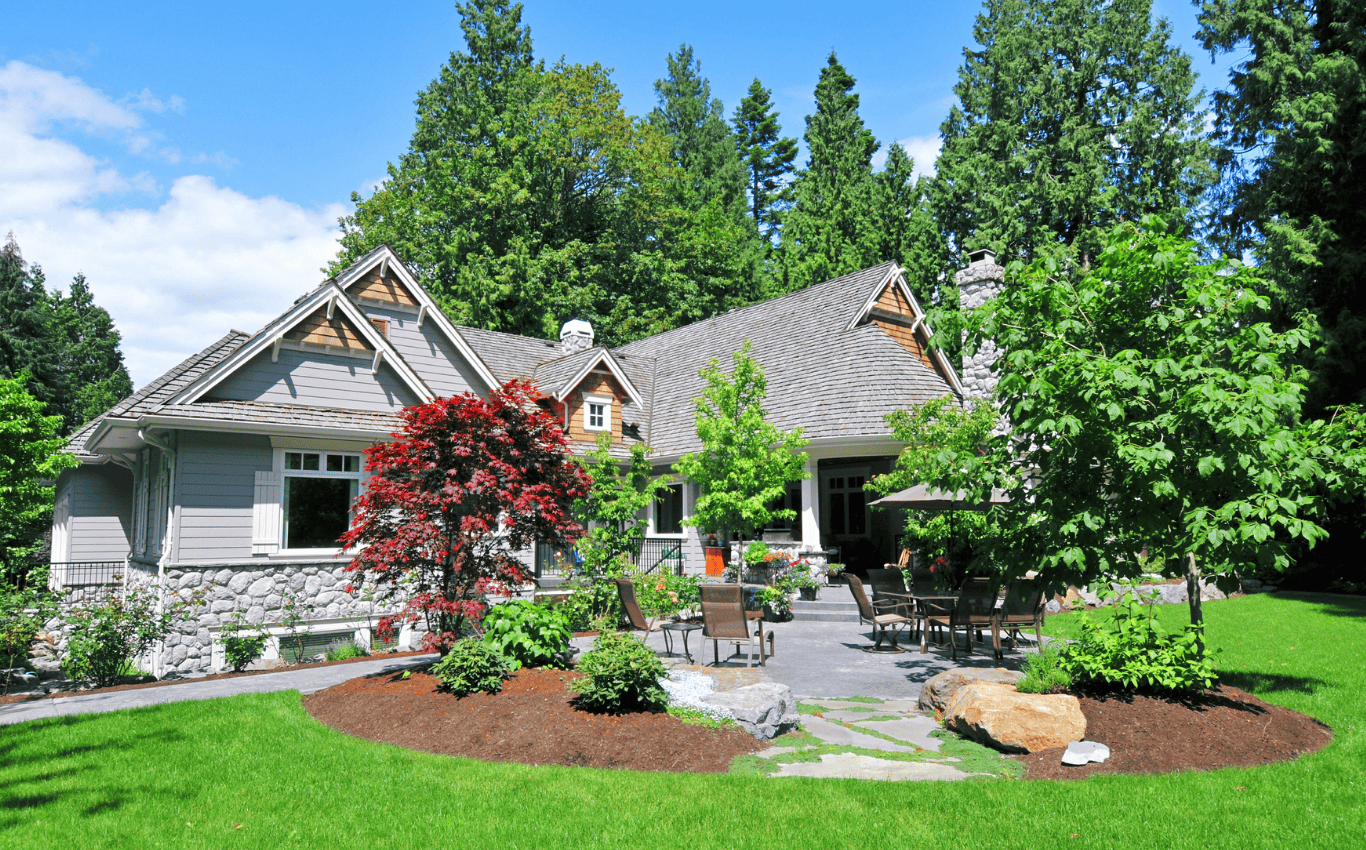 Long Island home with a professionally maintained lawn, fresh mulch beds, trimmed shrubs, and a clean backyard patio.