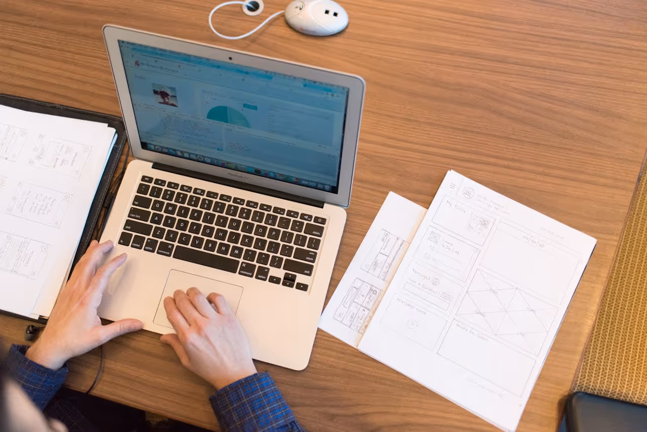 Person working on a laptop with paper documents on the desktop
