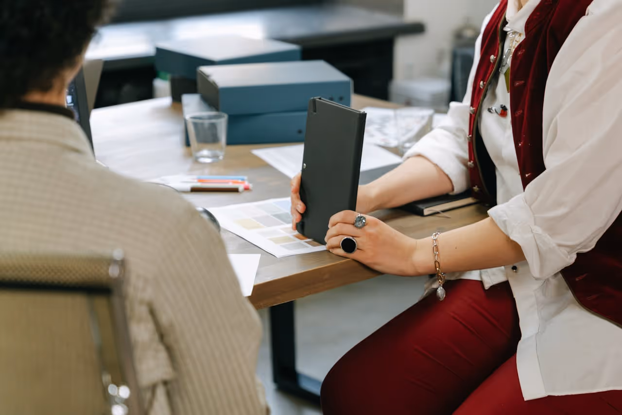 Two people gathered in an office with papers, folders and a note pad