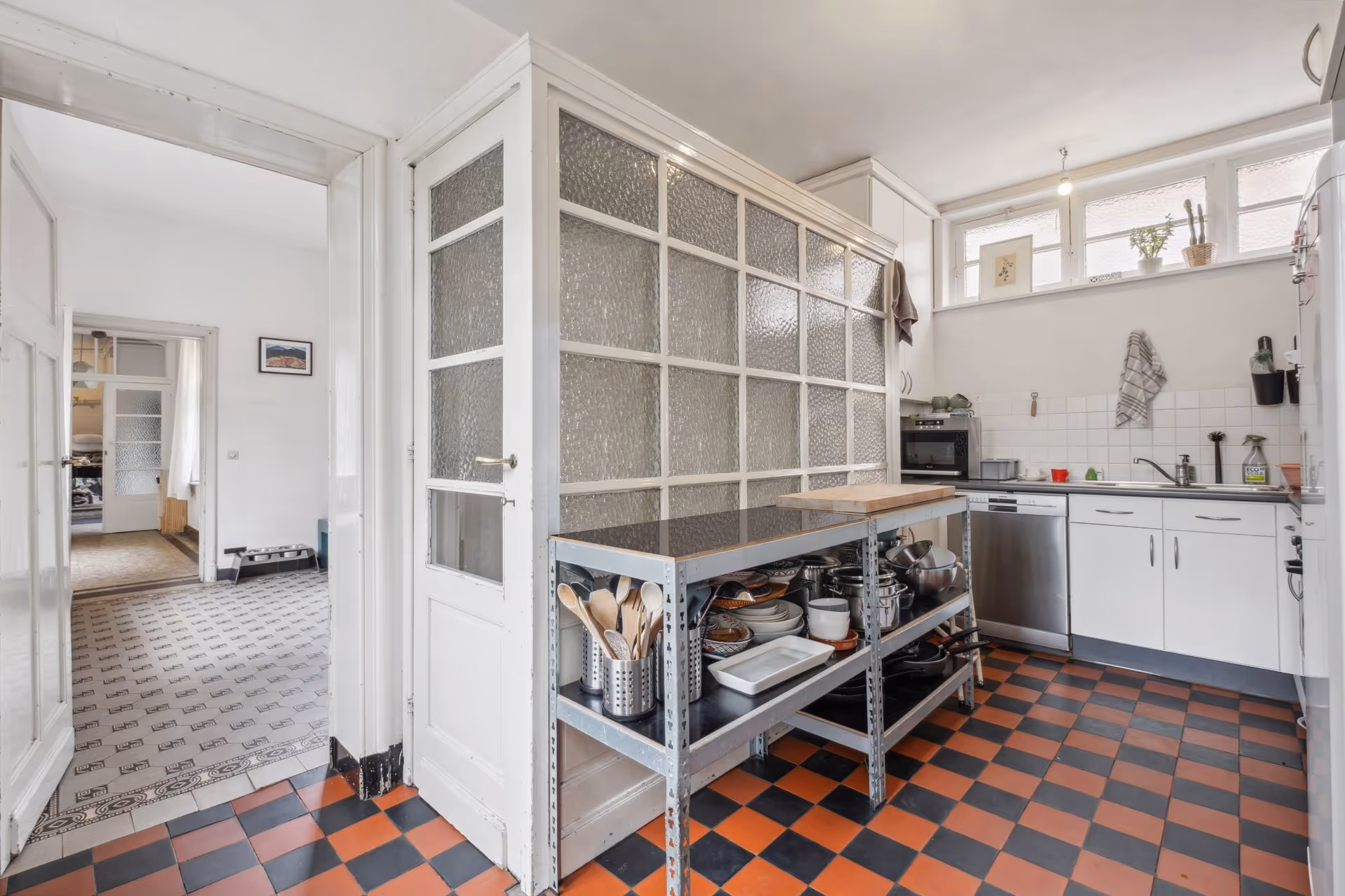 A kitchen with a checkered floor and white cabinets.