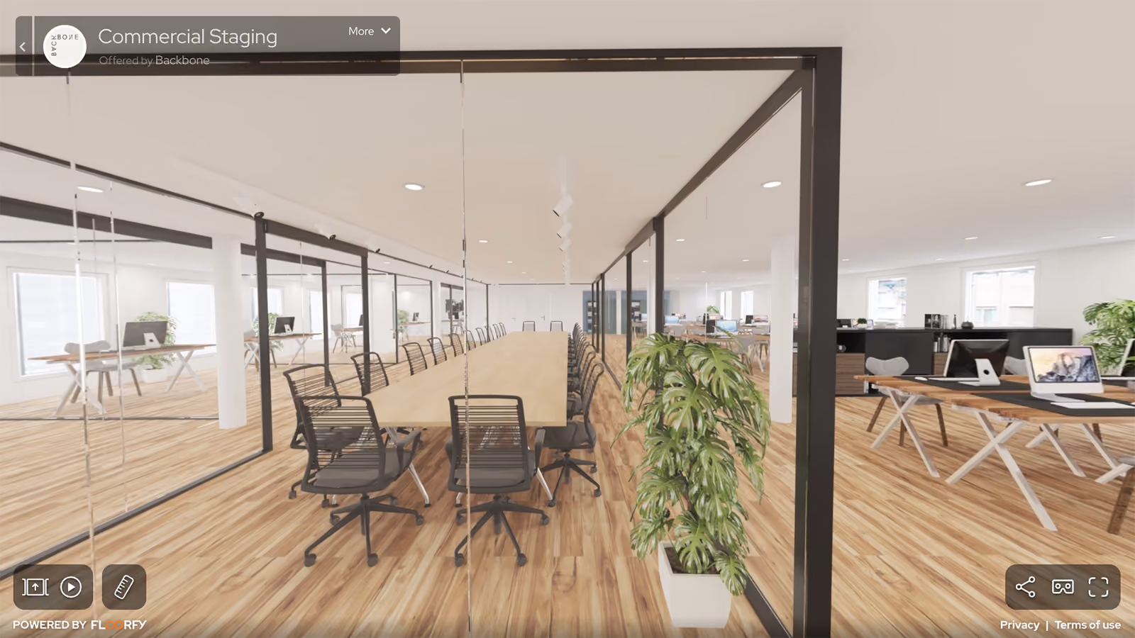 Spacious modern office with a long conference table, black chairs, wood floor, and plants inside glass walls.