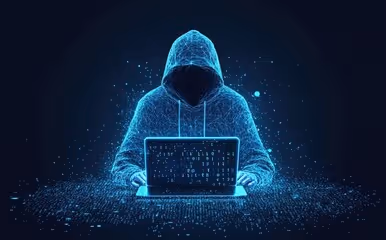 A hooded figure in digital blue sits at a laptop surrounded by code, symbolizing how generative AI empowers a single attacker to inflict large-scale damage. The image reflects the collapse of traditional perimeter defenses and the rise of identity- and behavior-based threats, showing how one person behind one screen can exploit the human layer and compromise enterprise security. 