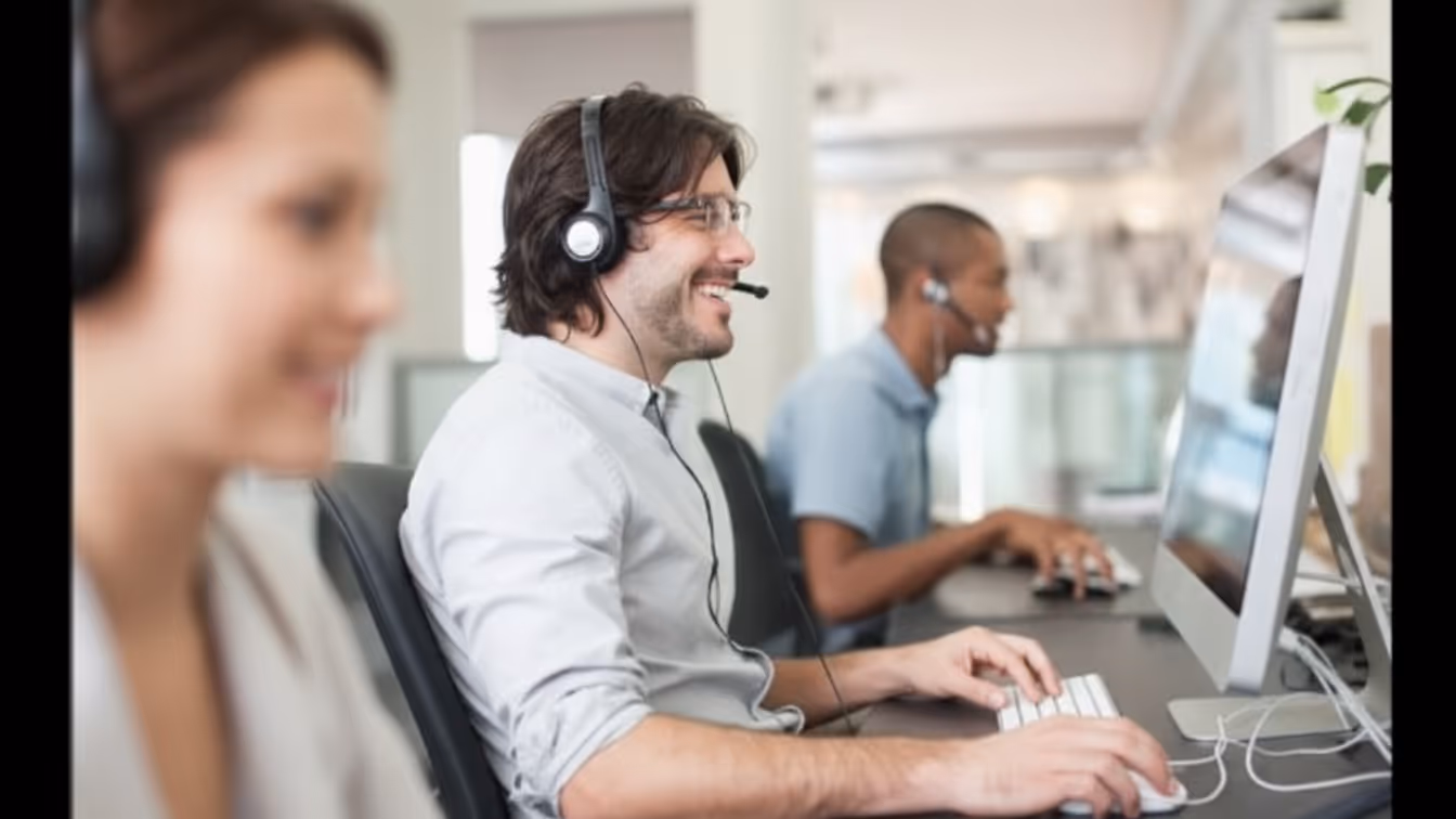 Business Process Outsourcing support agent using a headset in a modern office at night, illustrating user cyber risk in outsourced operations. 