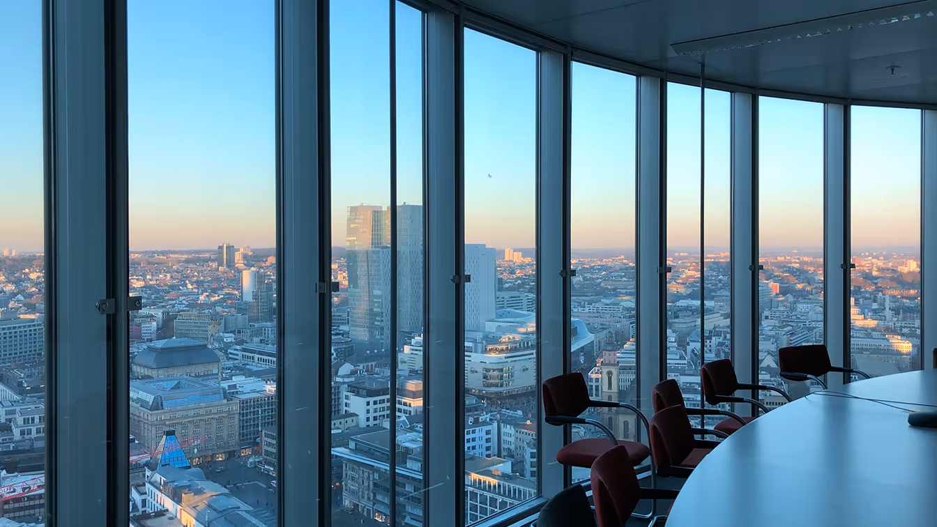 A high-rise conference room with floor-to-ceiling windows overlooking a city skyline at dusk, representing enterprise leadership navigating emerging agentic AI risk and governance.