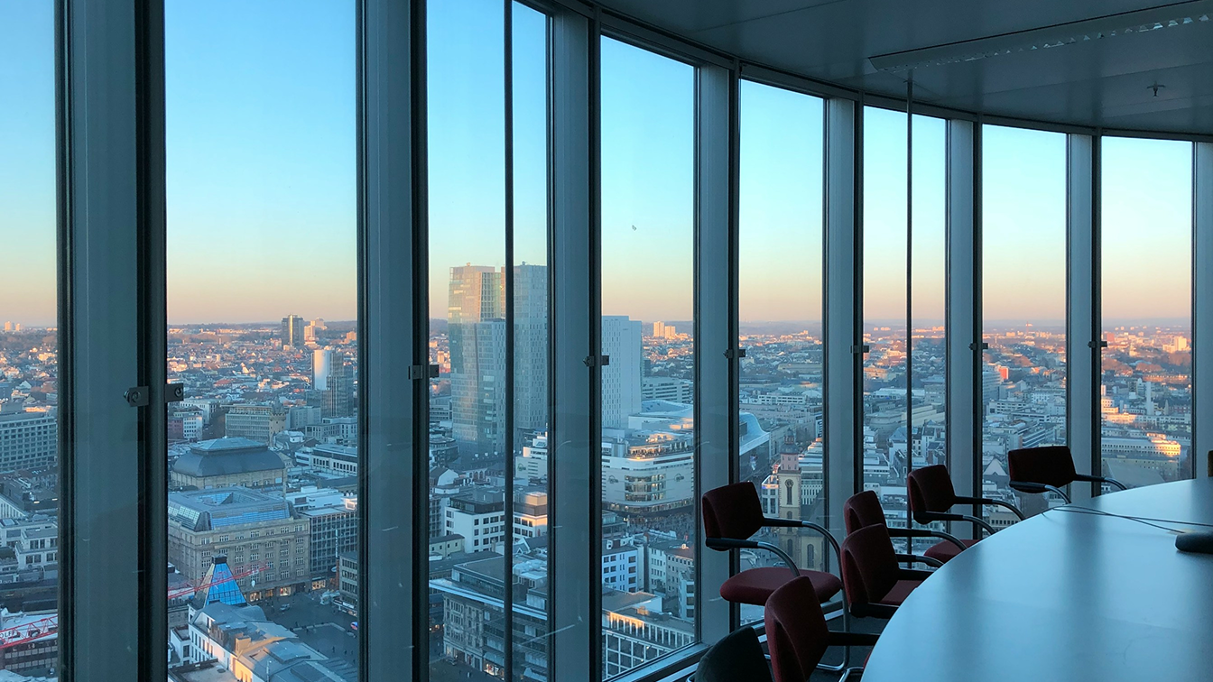 A high-rise conference room with floor-to-ceiling windows overlooking a city skyline at dusk, representing enterprise leadership navigating emerging agentic AI risk and governance. 