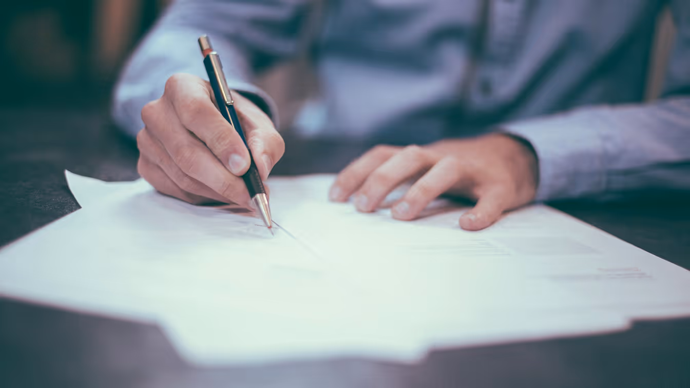 Legal professional signing documents, representing the high-value workflows targeted by business email compromise and wire fraud attacks
