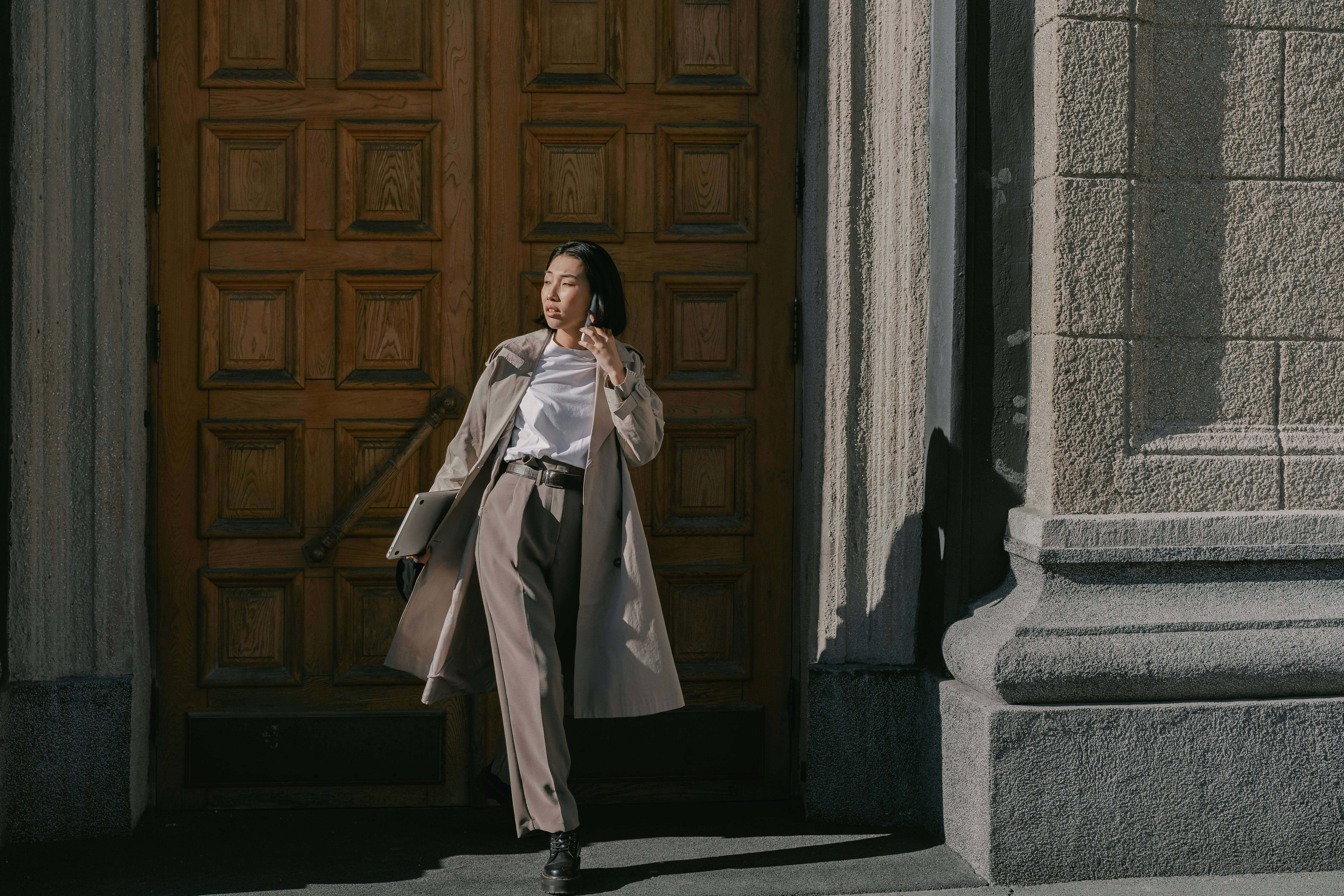 A businesswoman moving between meetings while taking a phone call. Illustrates the modern executive whose multi-channel workflow demands continuous, dynamic defense at the User Layer through Dune Security's User Adaptive Risk Management platform.