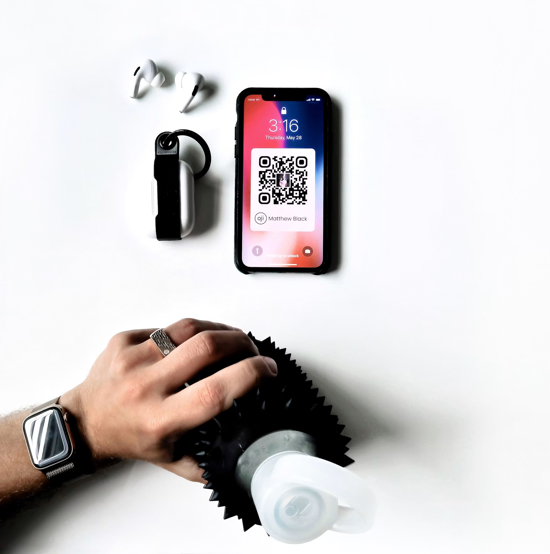 Phone showing a QR code pass beside wireless earbuds on a white desk, reflecting mobile quishing risk