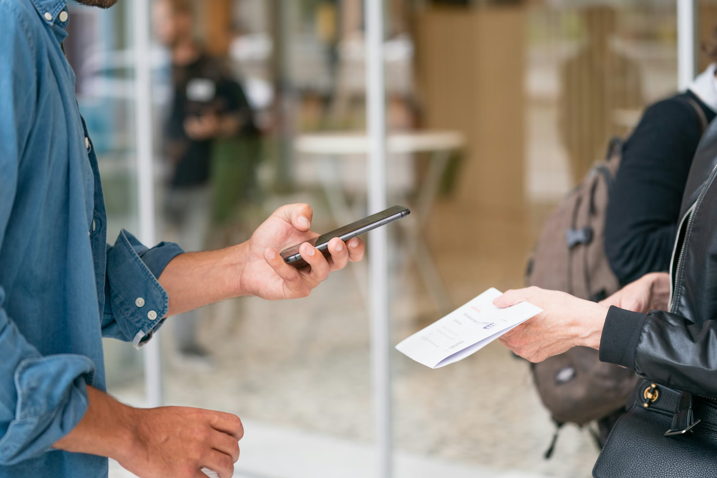 Hand scanning a printed QR code on a restaurant table with a phone, a placement often used in quishing attacks