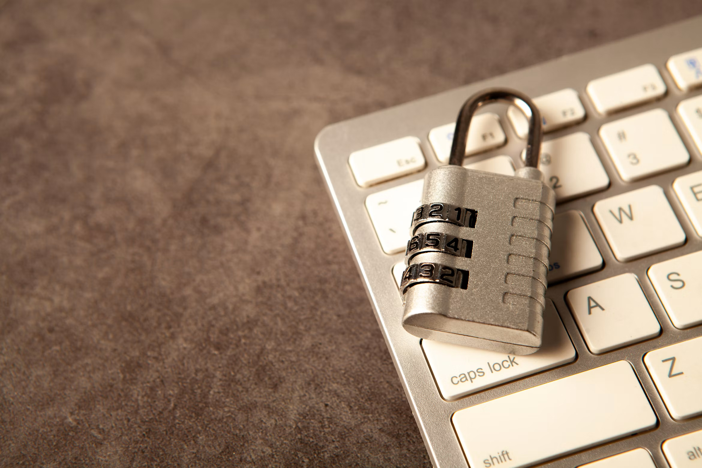Combination padlock resting on a computer keyboard, representing the credential controls that limit lateral movement