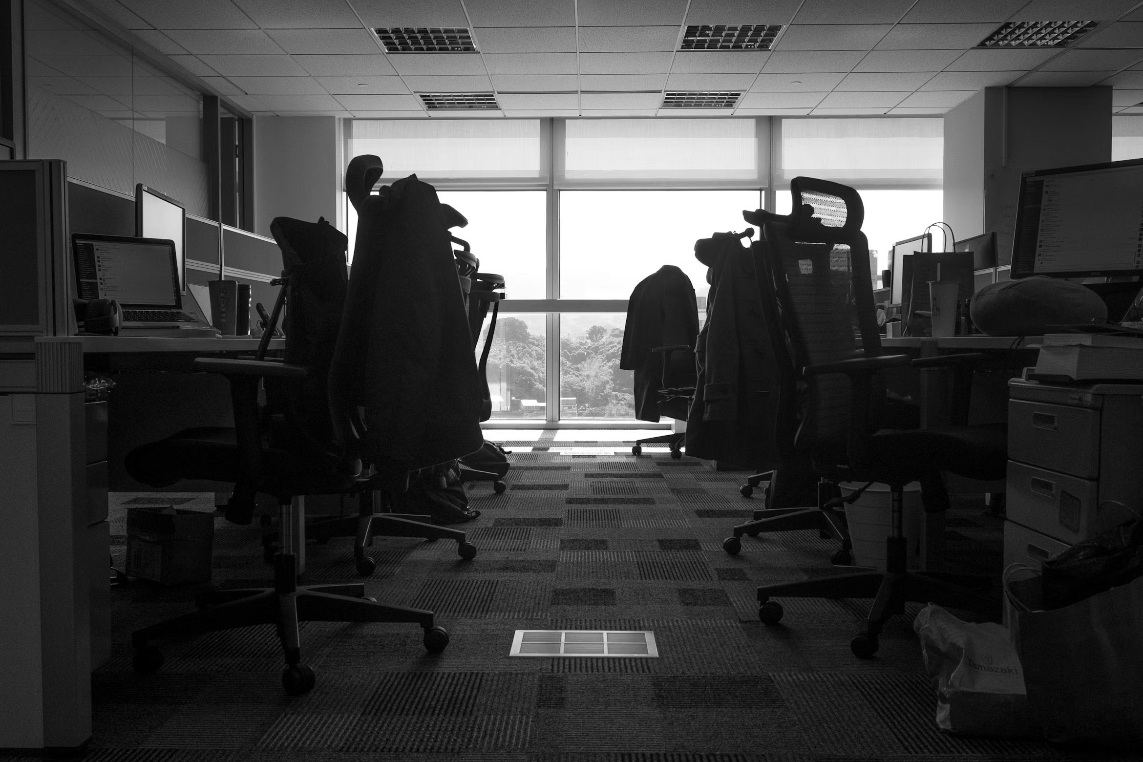 Dark, empty open-plan office after hours with monitors still on, evoking the blind spots where insider risk hides