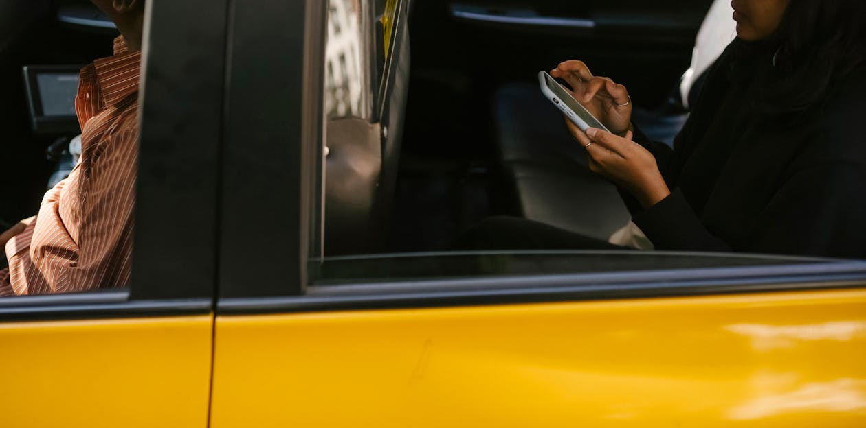 Passenger using a smartphone in the back of a taxi, showing the on-the-go distraction that feeds employee fatigue