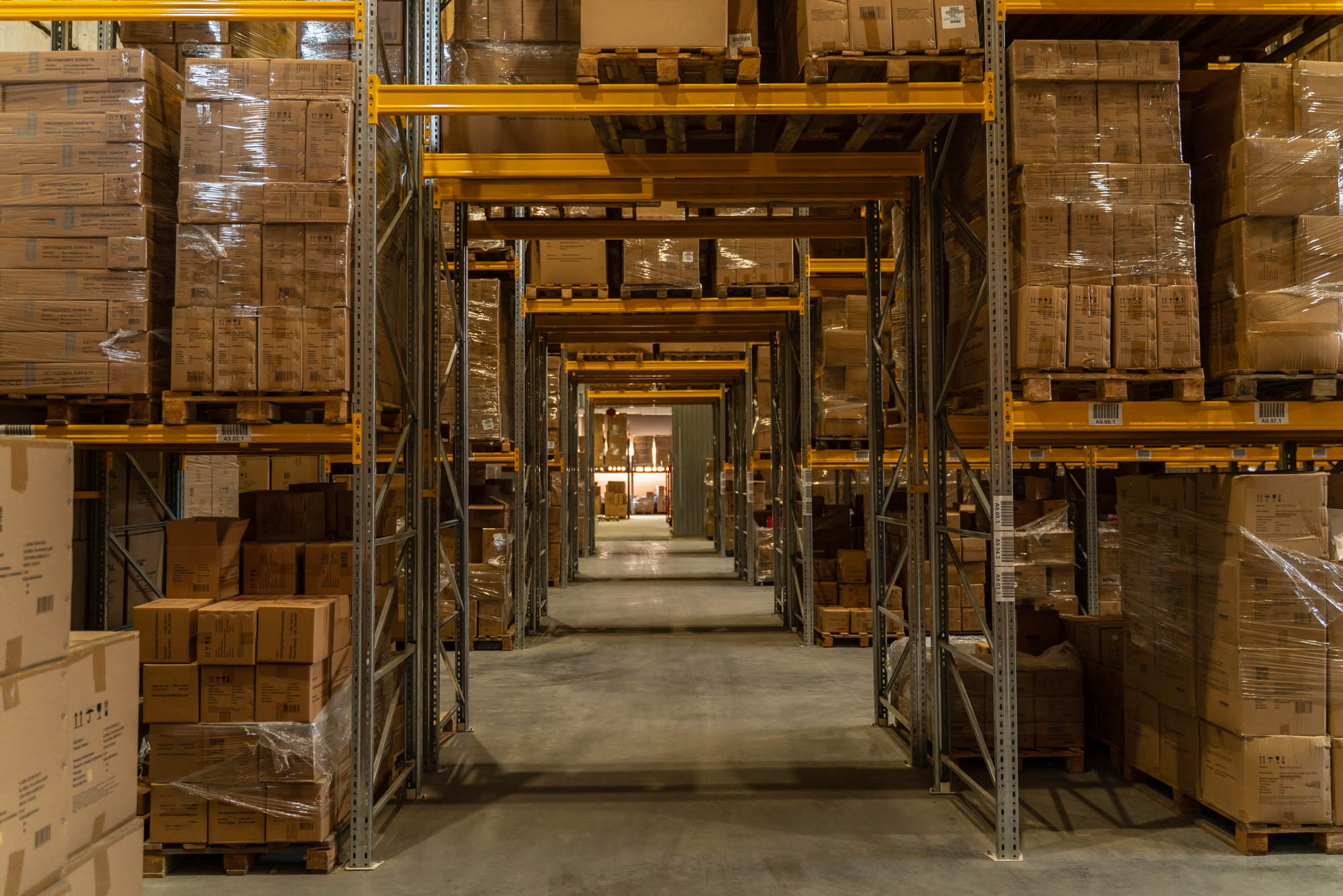 Large warehouse aisle filled with neatly stacked cardboard boxes on metal shelves.