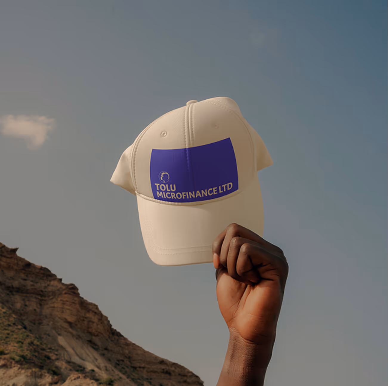 Tolu Microfinance brand identity — branded cap held against a coastal sunset backdrop