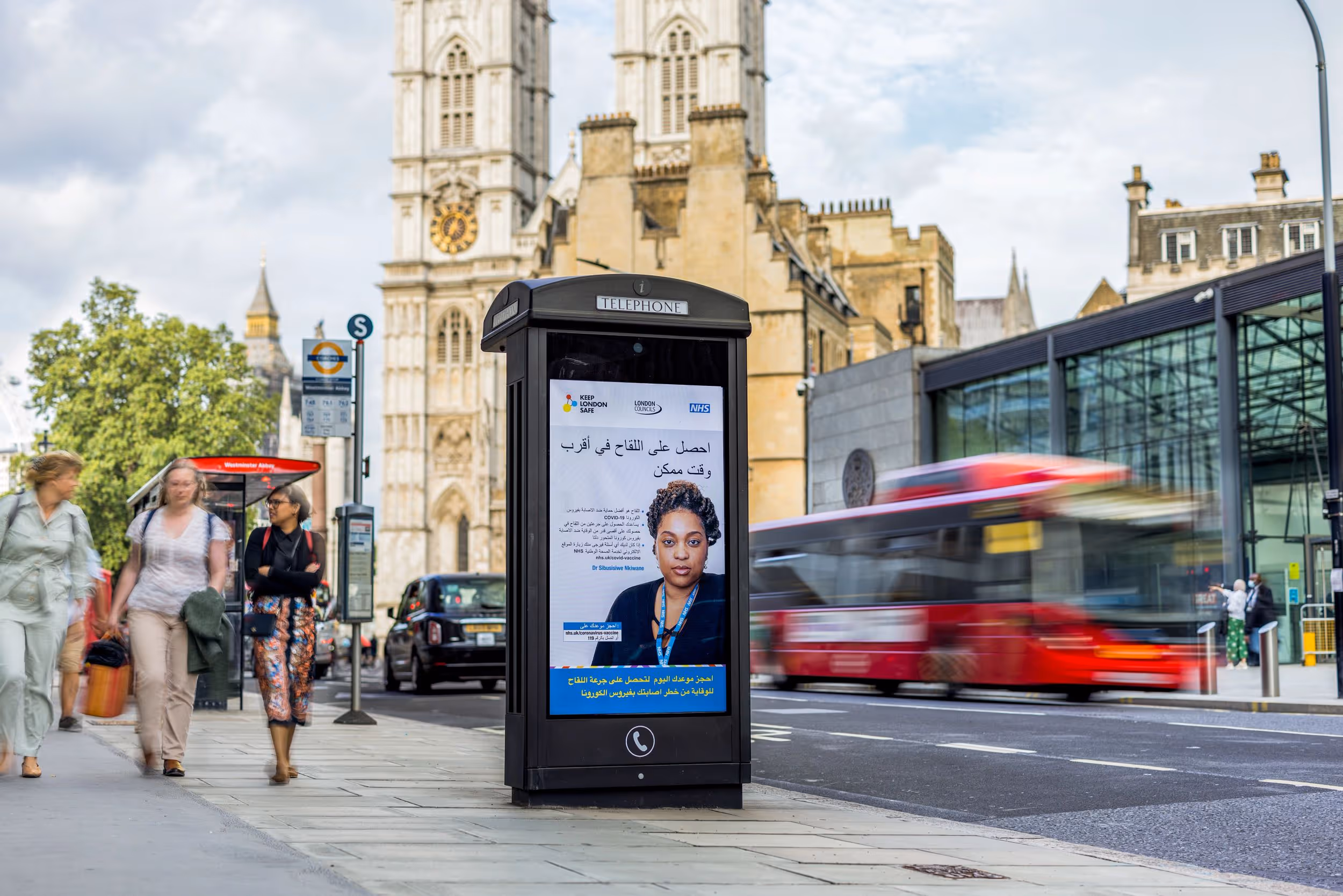 An NHS digital screen campaign in London with traffic flowing by in the background