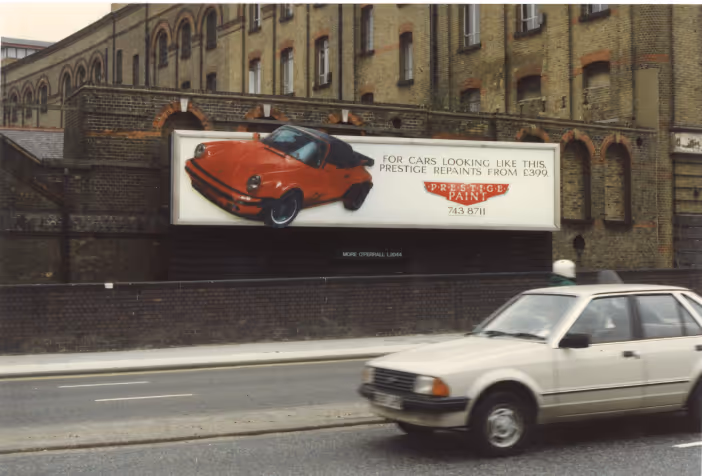 Prestige Paint ad on a billboard in 1996 with a car driving by