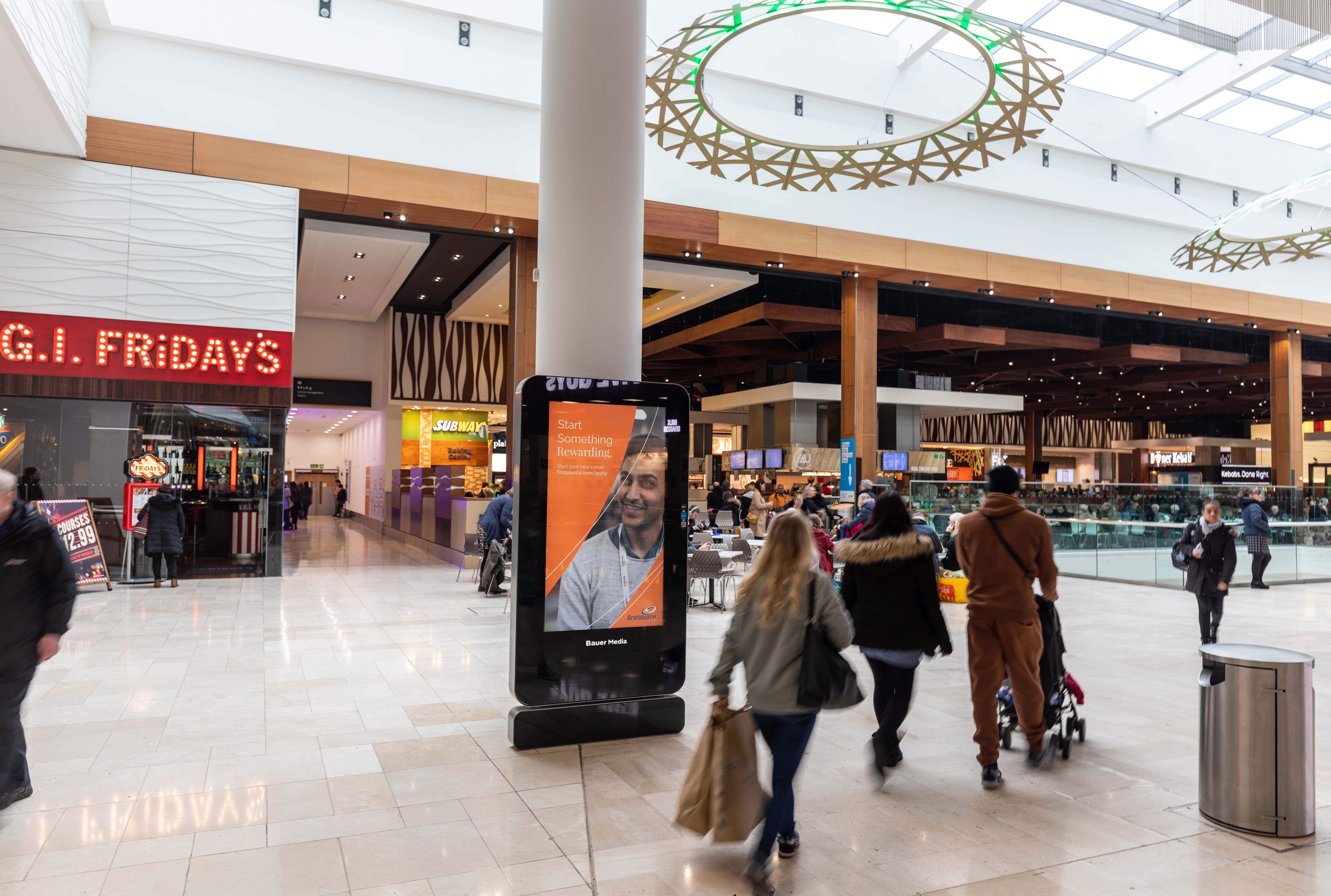 Firstsource's "Start something different" orange ad located in a busy shopping centre