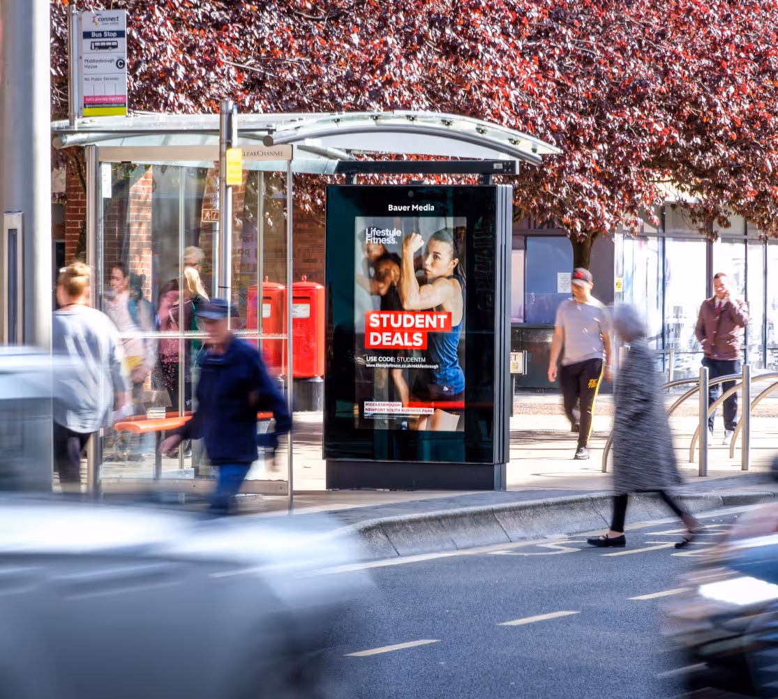 Lifestyle Fitness advertising on a roadside digital screen with people walking by
