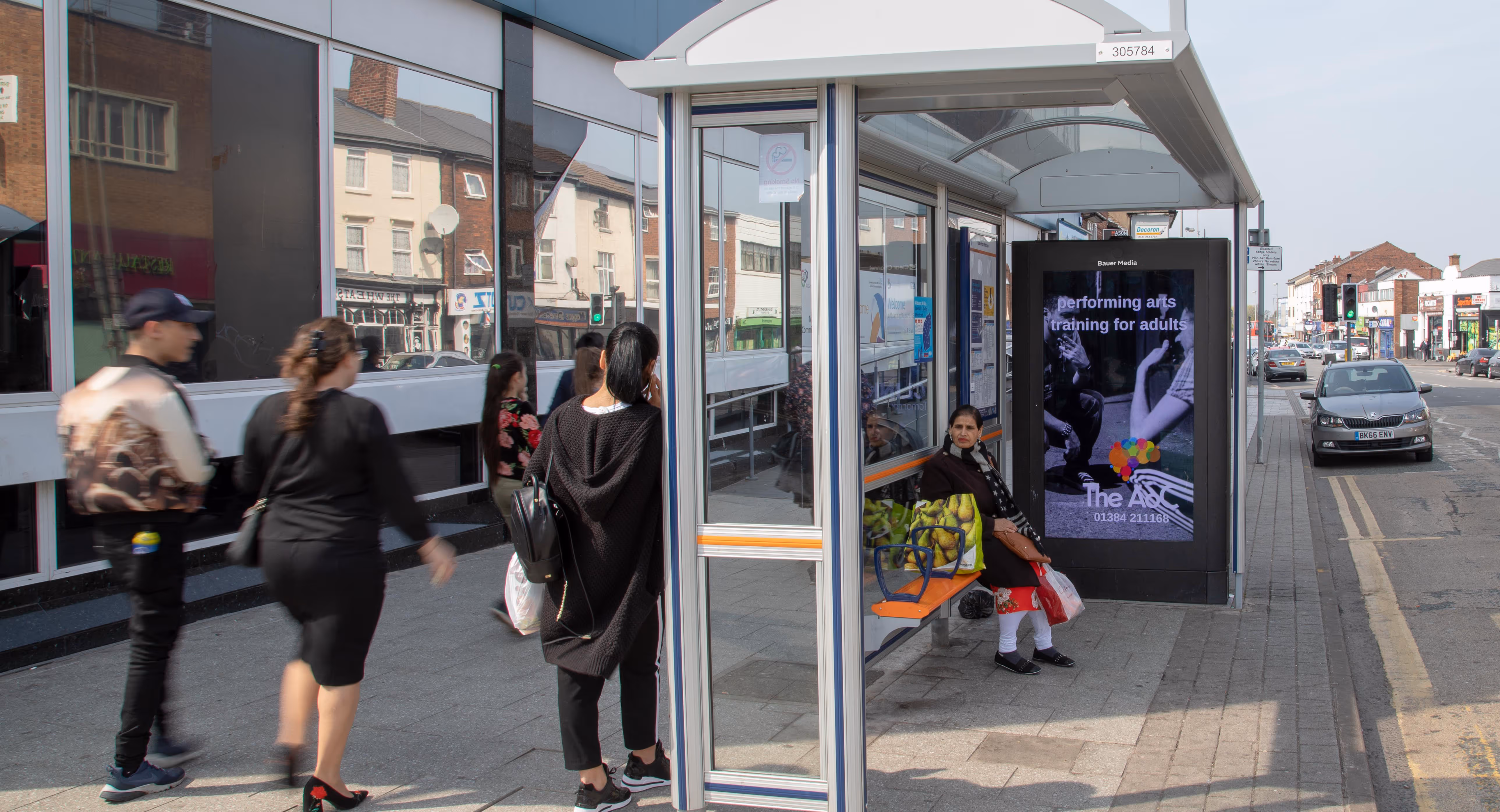 Digital bus shelter screen displaying a performing arts campaign