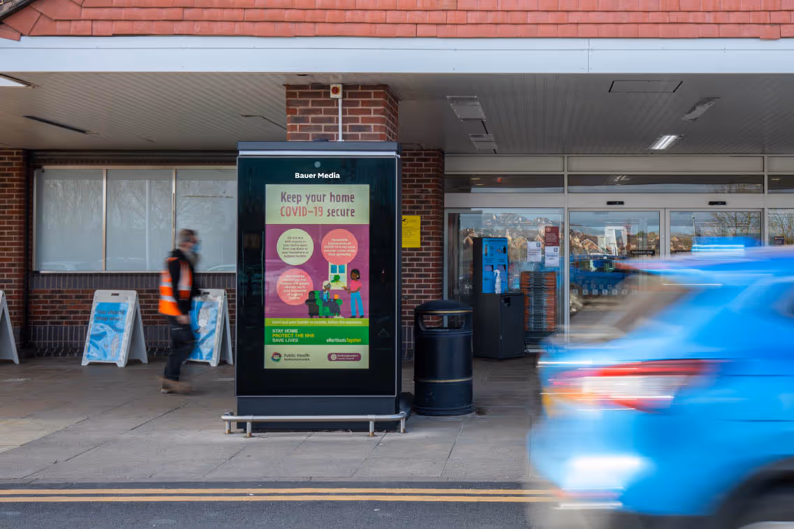 Northamptonshire County Council's "Covid 19" ad outside a busy Sainsbury's