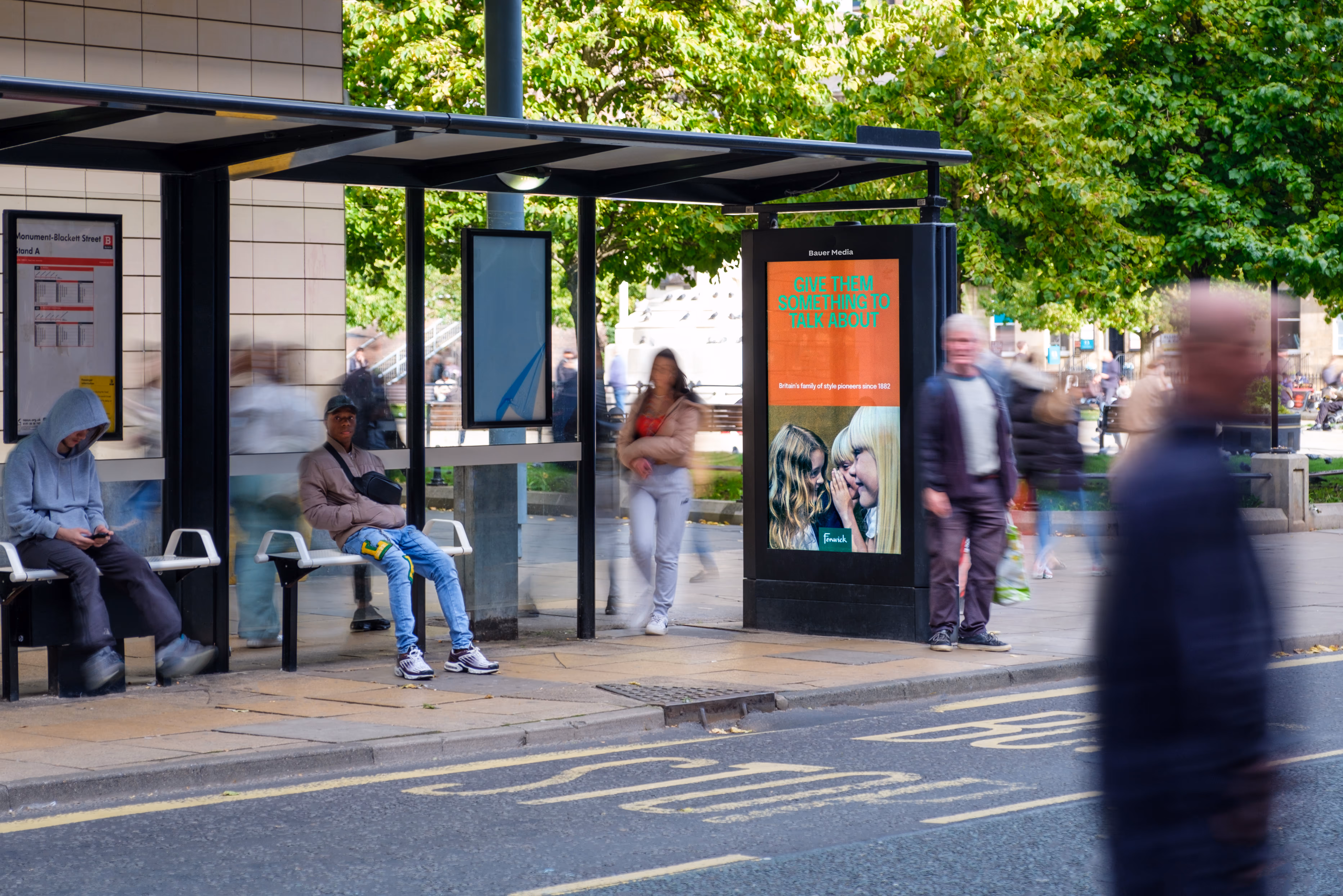 Digital bus shelter with people sat within the shelter